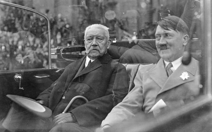 The new chancellor, Adolf Hitler, passes by the people of Berlin next to President Paul von Hindenburg.