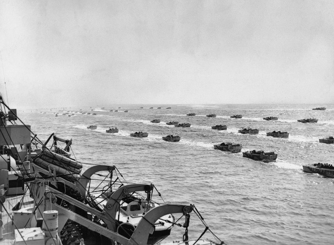 A group of Landing Craft Assault vessels are shown passing by a landing ship during training exercises prior to the Normandy invasion.