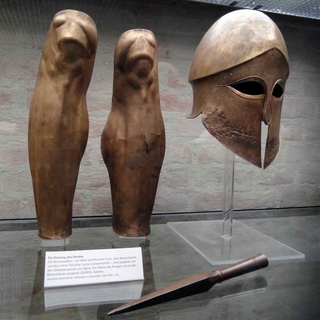 Greaves, Corinthian helmet, and spear tip from the tomb of Denda. The name of the warrior (Denda) is engraved on the left greave. From a Greek workshop in South Italy, 500–490 BC.