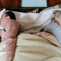 Diverse spouses sleeping on bed under plaid